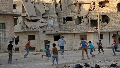 a group of kids playing soccer in a destroyed building