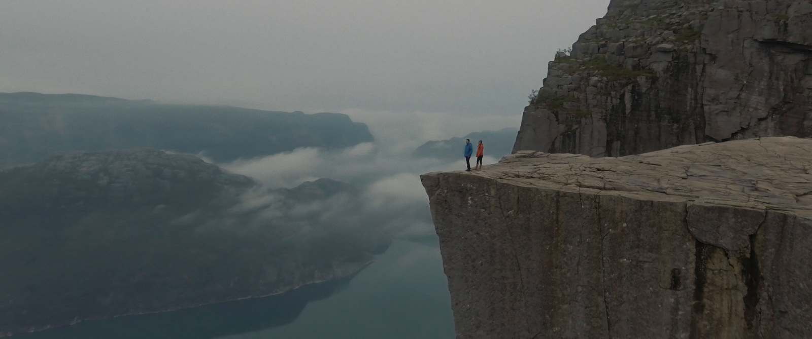 two people standing on the edge of a cliff