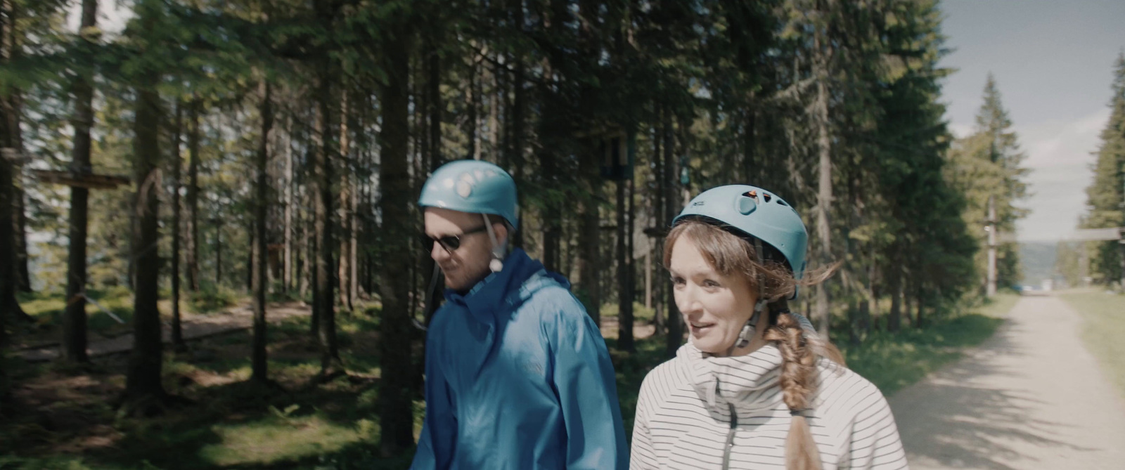 two people wearing blue hats walking down a path in the woods