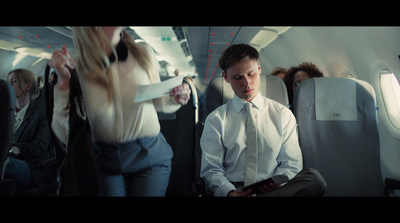 a man in a white shirt and tie sitting on an airplane