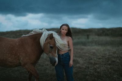 a woman standing next to a horse in a field