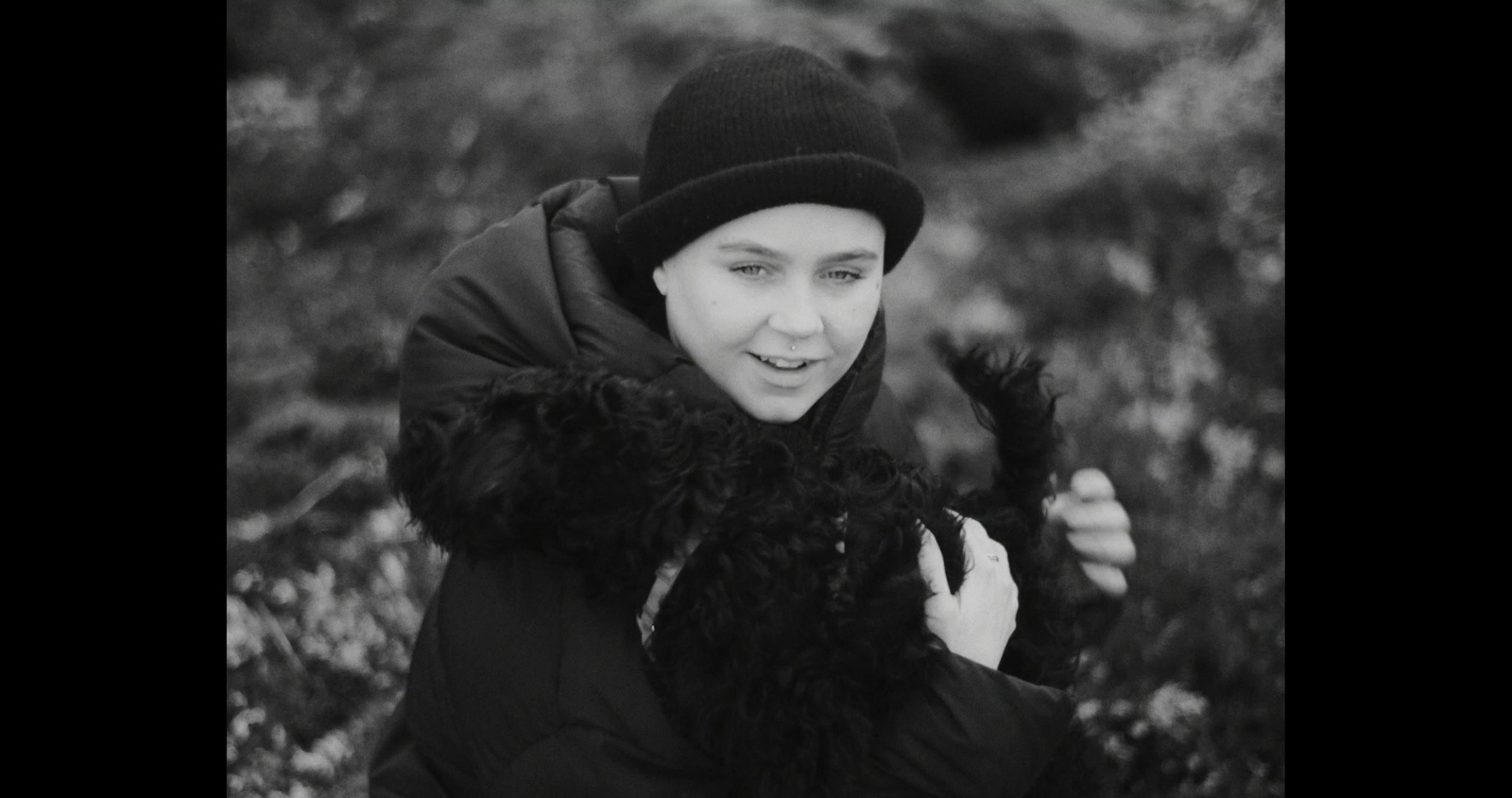 a black and white photo of a woman wearing a hat and scarf