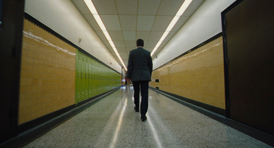 a man in a suit walking down a hallway