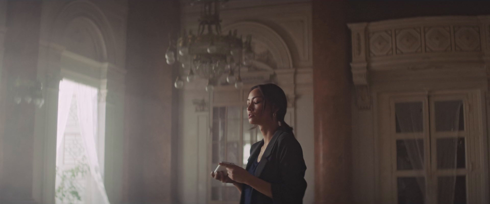 a woman standing in a room with a chandelier