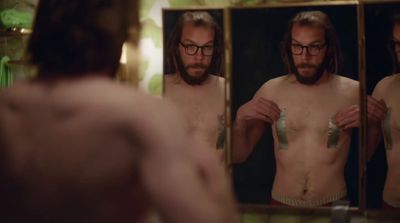 a shirtless man is looking at himself in the mirror