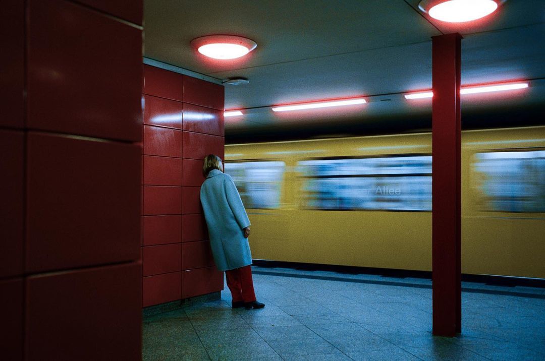 a woman standing in a subway station waiting for a train