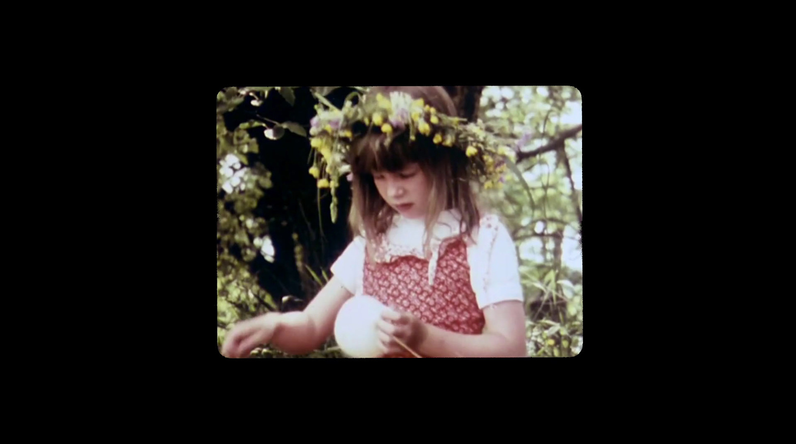 a young girl wearing a wreath of flowers on her head