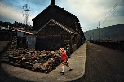 a woman walking down a street next to a building