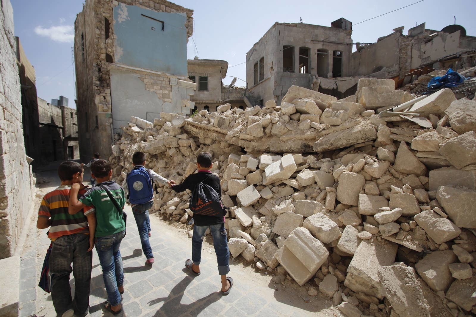 a group of young men standing next to a pile of rubble