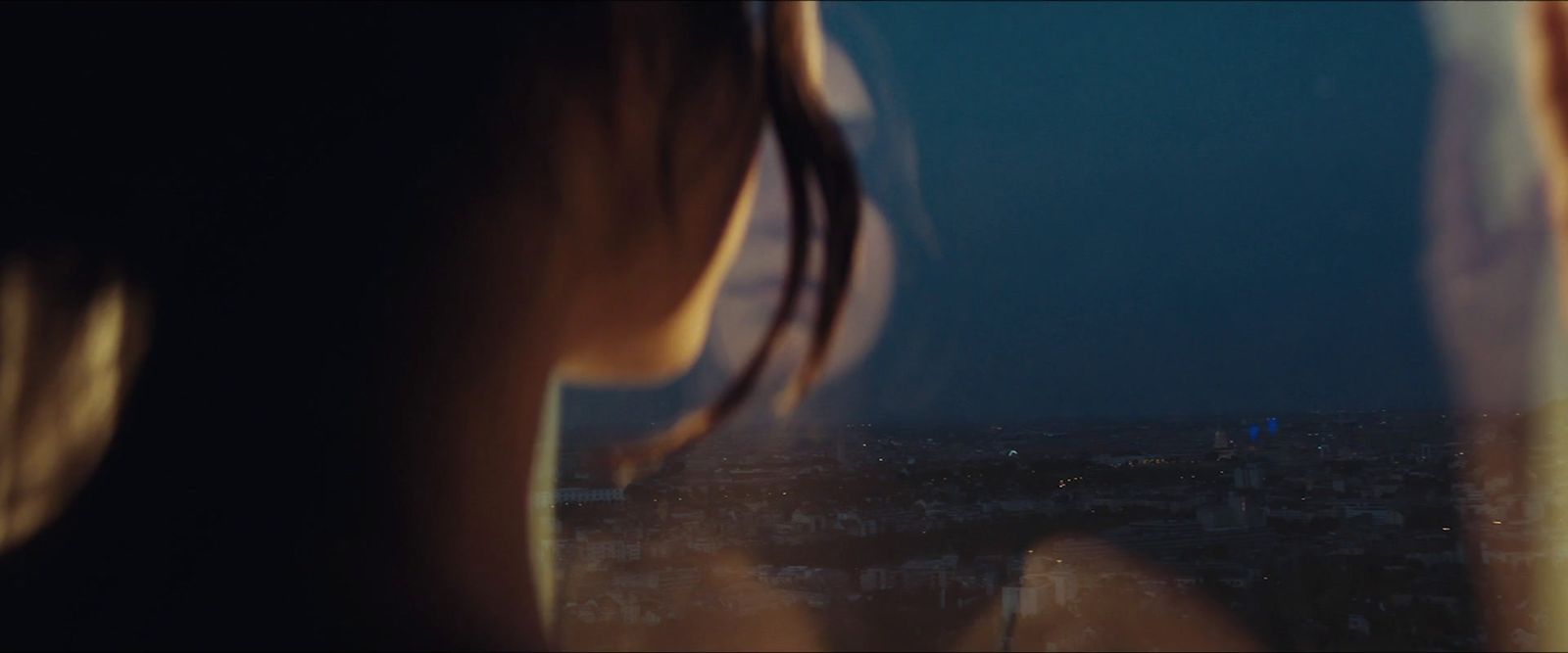 a woman looking out a window at a city at night