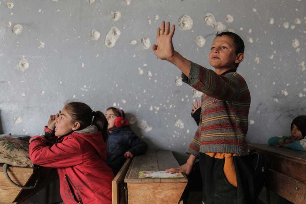 a group of children in a room with a wall full of bullet holes