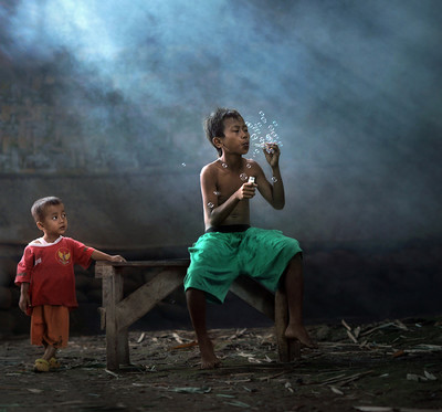 a young boy sitting on a bench next to a young boy