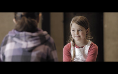 a little girl sitting in front of a woman