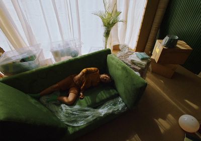 a person laying on a green couch in a living room