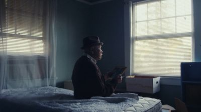 a man sitting on a bed reading a book