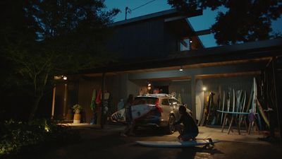 a person sitting on a surfboard in front of a house