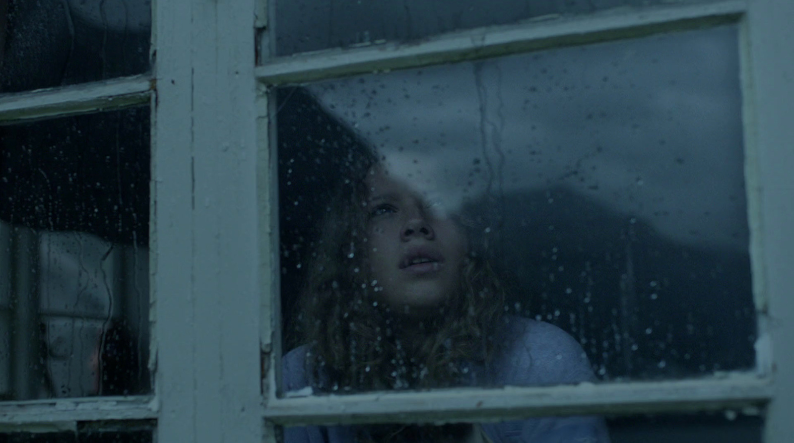 a woman looking out of a window in the rain