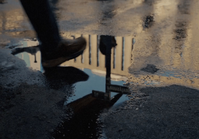 a person walking across a wet street next to a parking meter