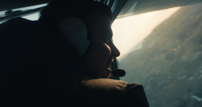 a man wearing a headset looking out the window of a plane