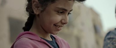 a young girl smiles as she looks at her cell phone