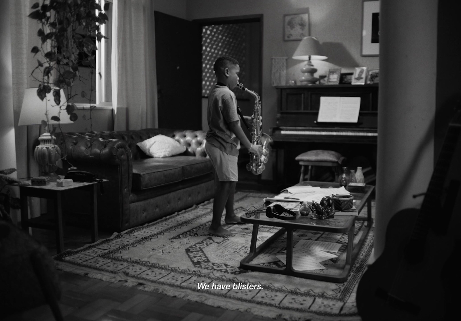 a boy standing in a living room holding a saxophone