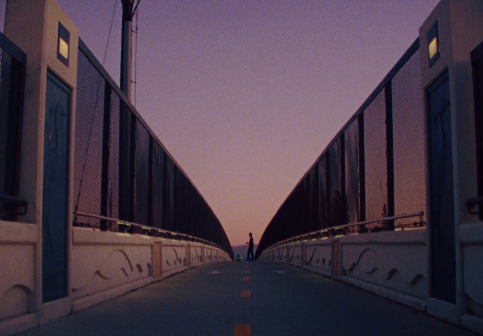 a person walking across a bridge at dusk