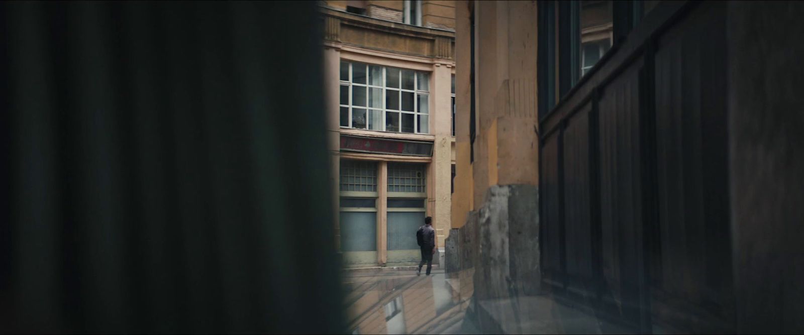 a man walking down a street next to a tall building