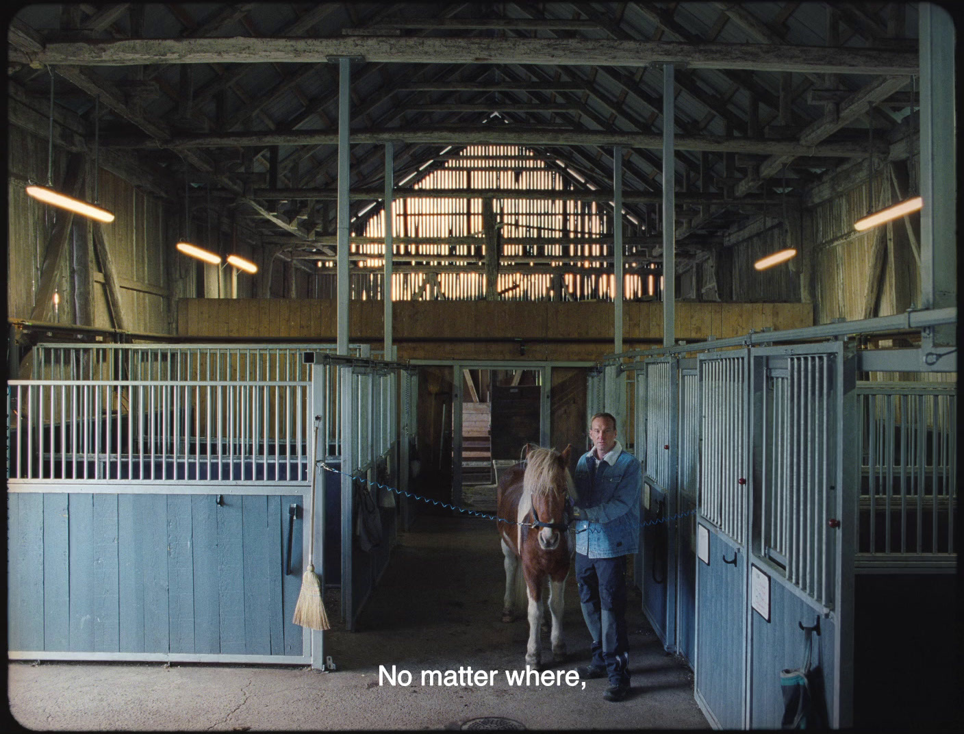 a man standing next to a horse inside of a barn