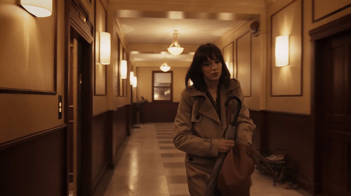 a woman walking down a hallway with a bag