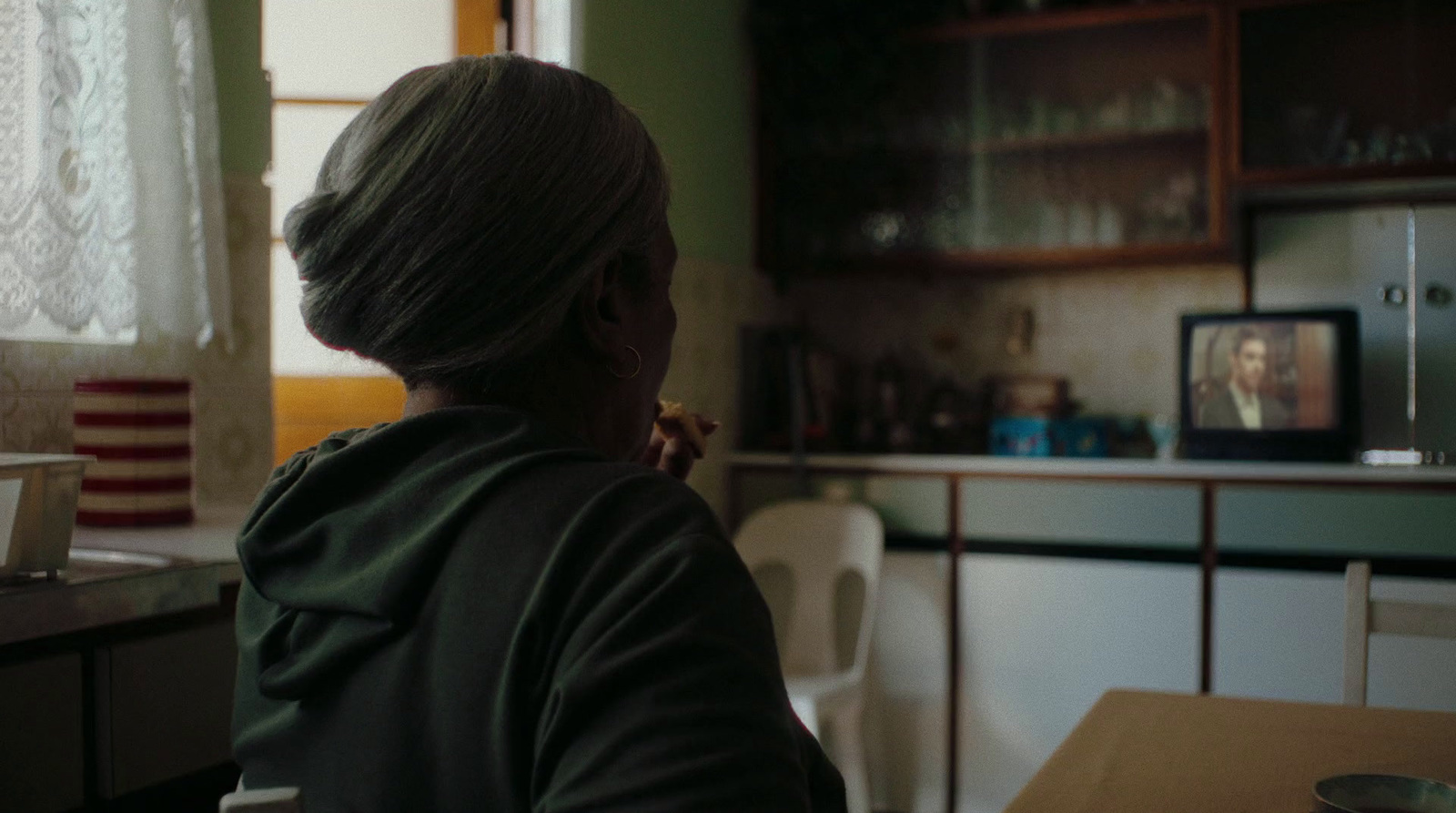 a woman sitting at a table in front of a tv