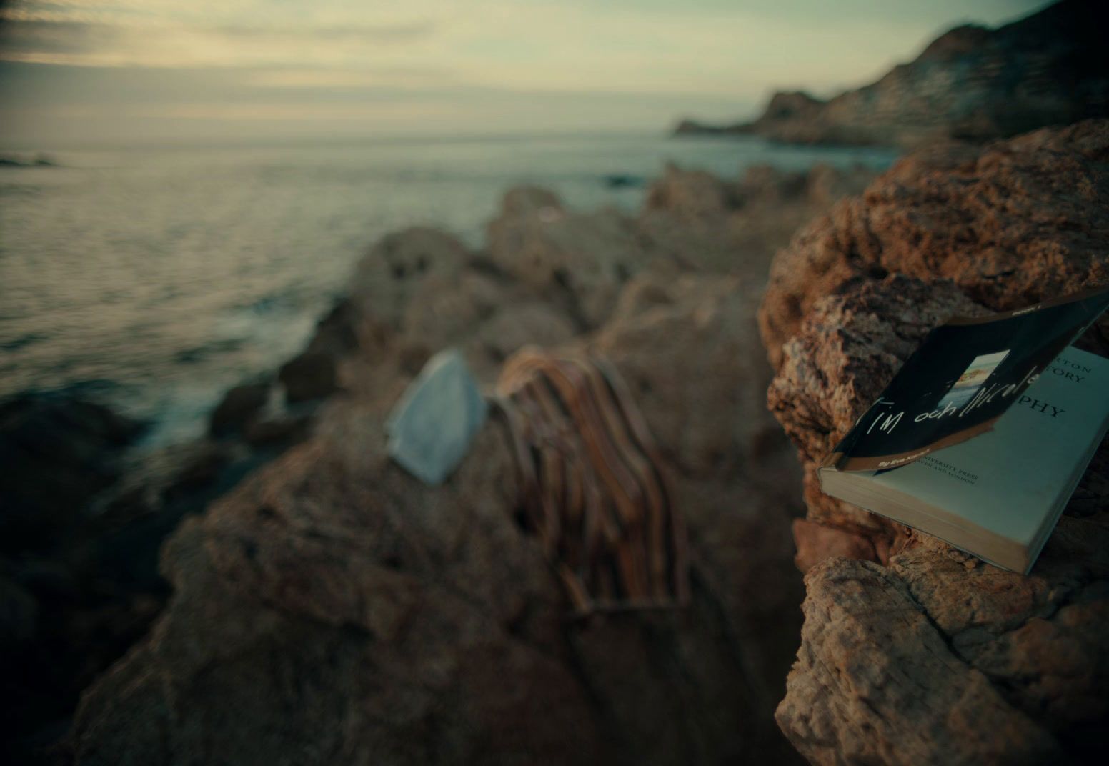 a book sitting on top of a rock next to the ocean