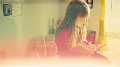 a young girl sitting on the floor reading a book