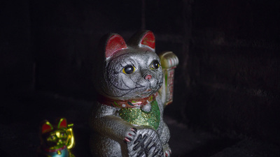 a cat figurine sitting next to another cat figurine