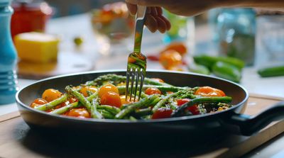 a person using a fork to stir vegetables in a pan