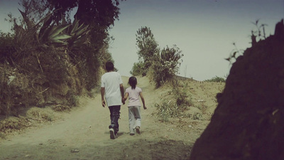 a man and a little girl walking down a dirt road