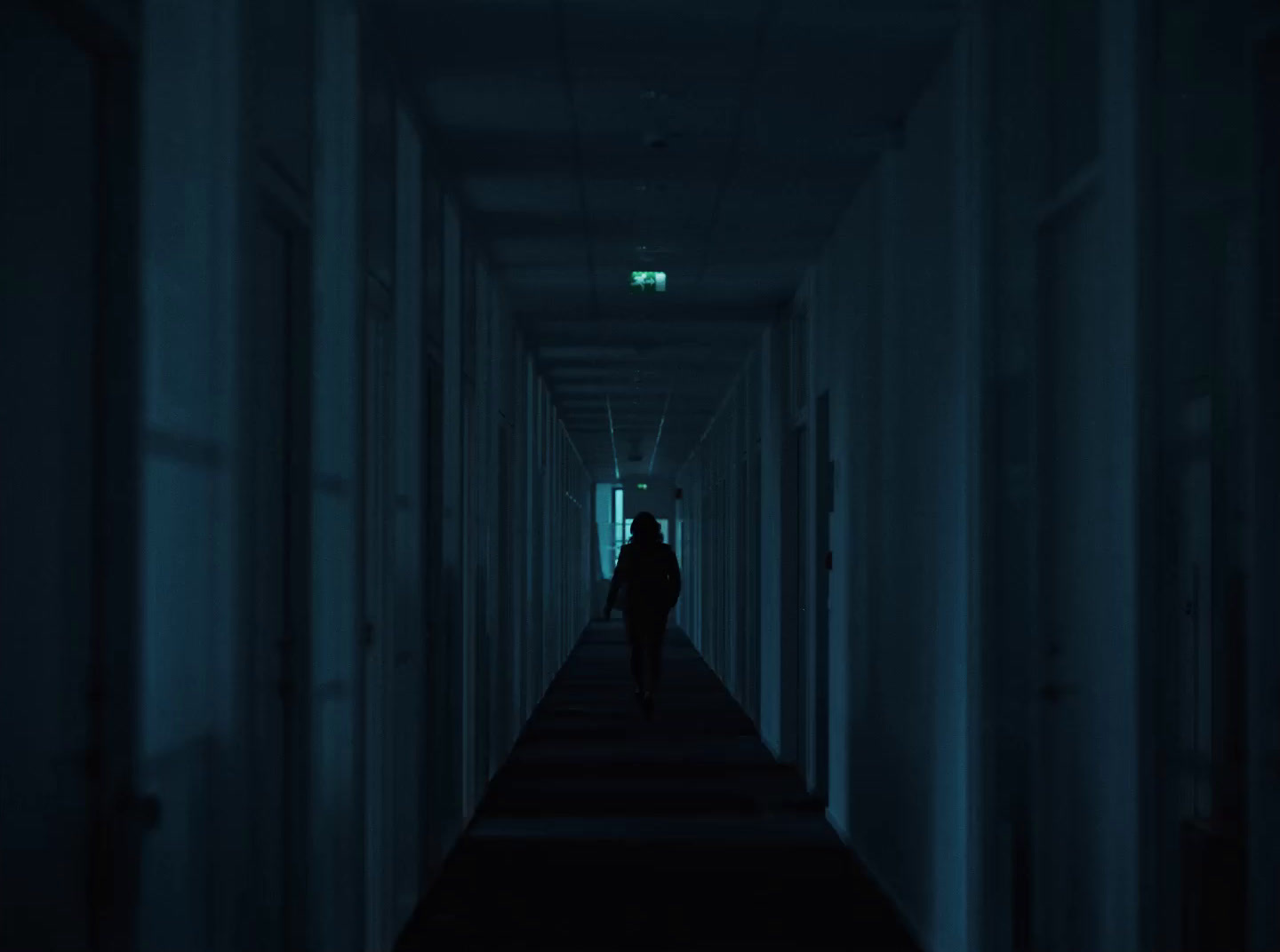 a person walking down a long hallway in the dark