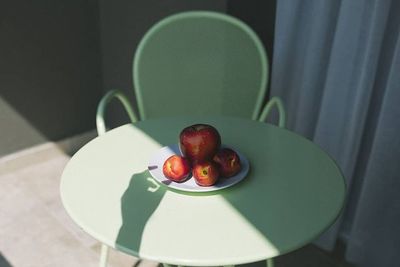 a plate of apples sitting on a green table