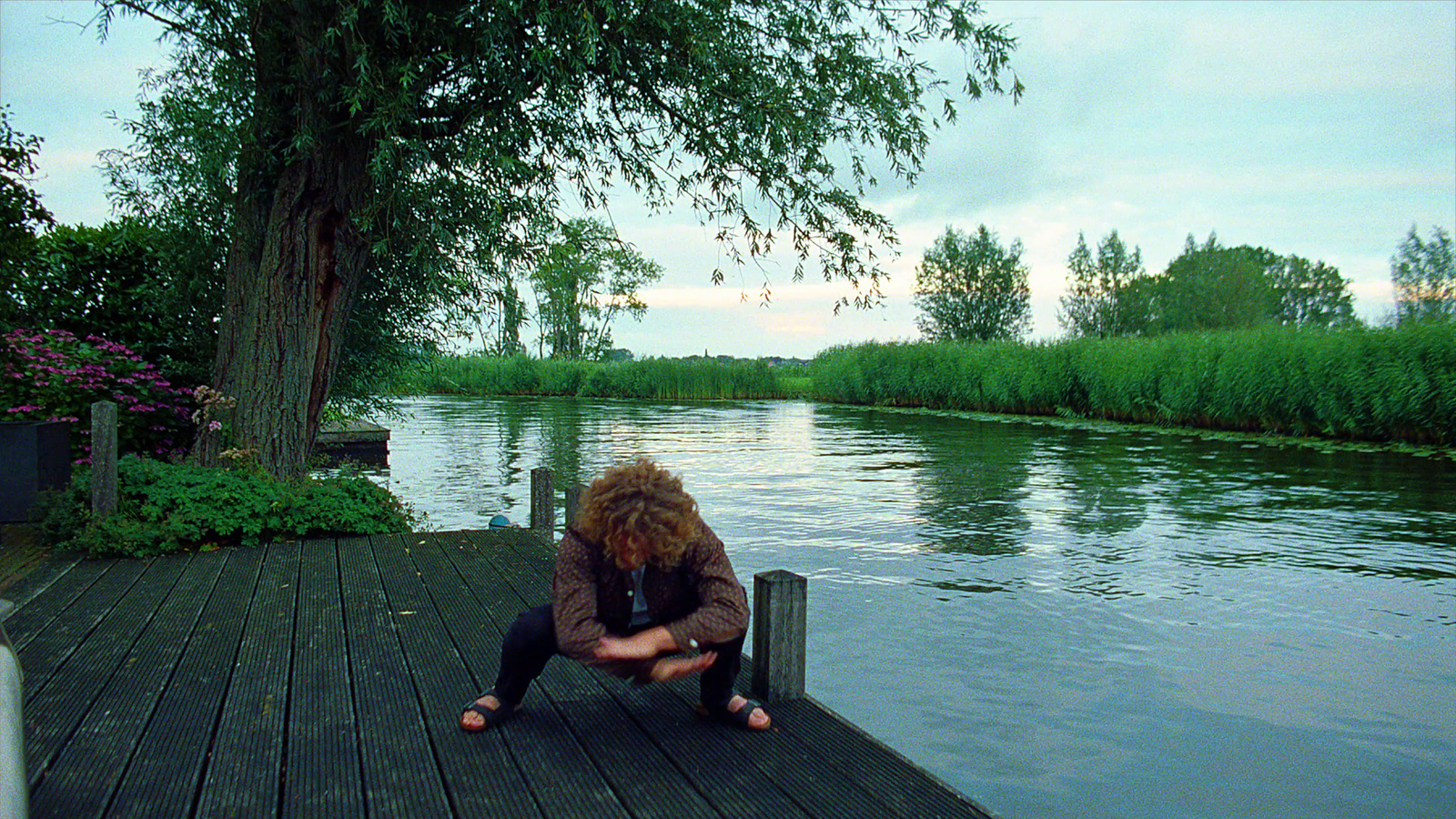 a woman sitting on a dock next to a body of water