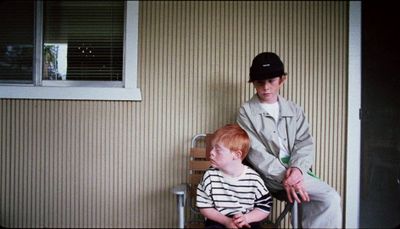 a man sitting on a chair next to a little boy