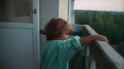 a little girl standing on a balcony next to a door