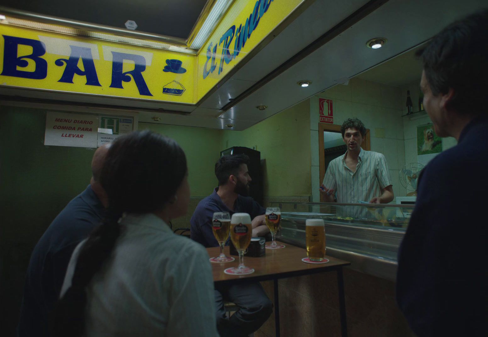 a group of people sitting at a bar with beers