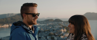 a man and woman are looking at each other while standing on top of a mountain