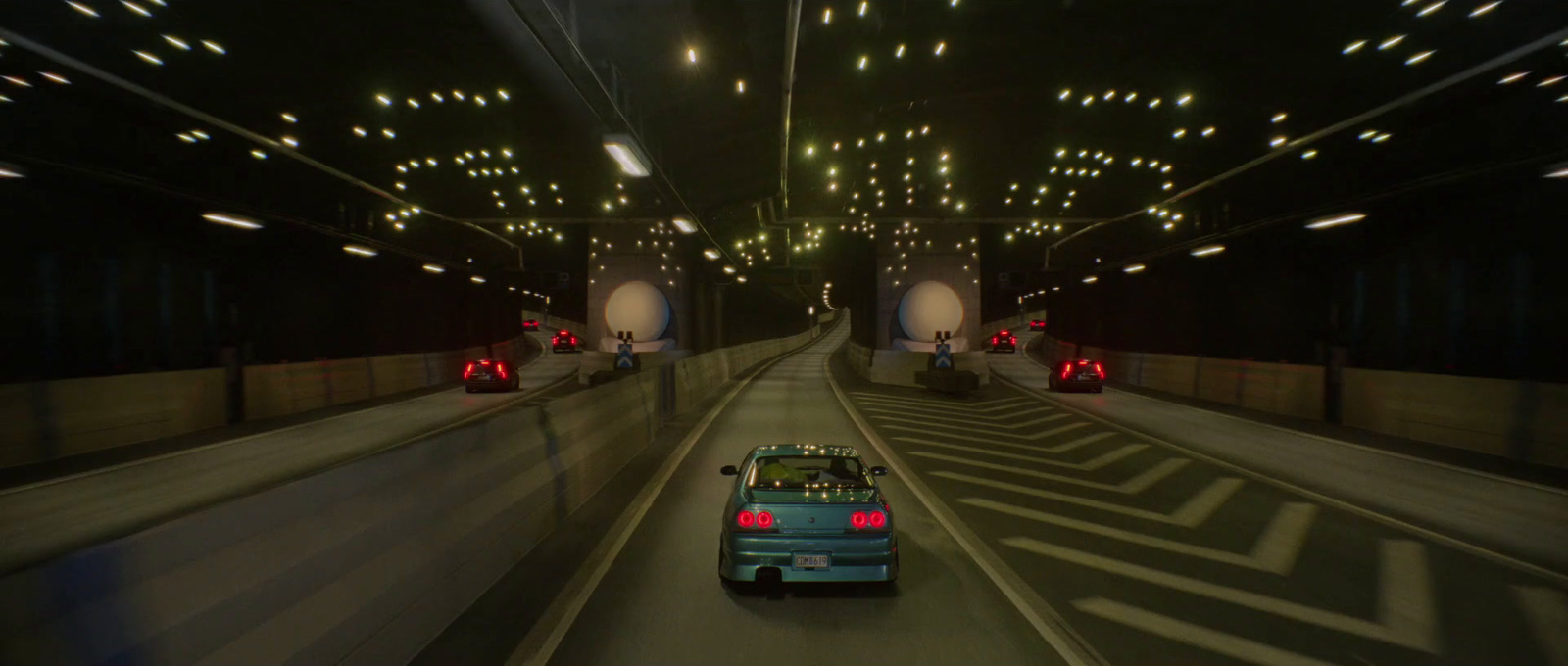 a car driving through a tunnel with lights on