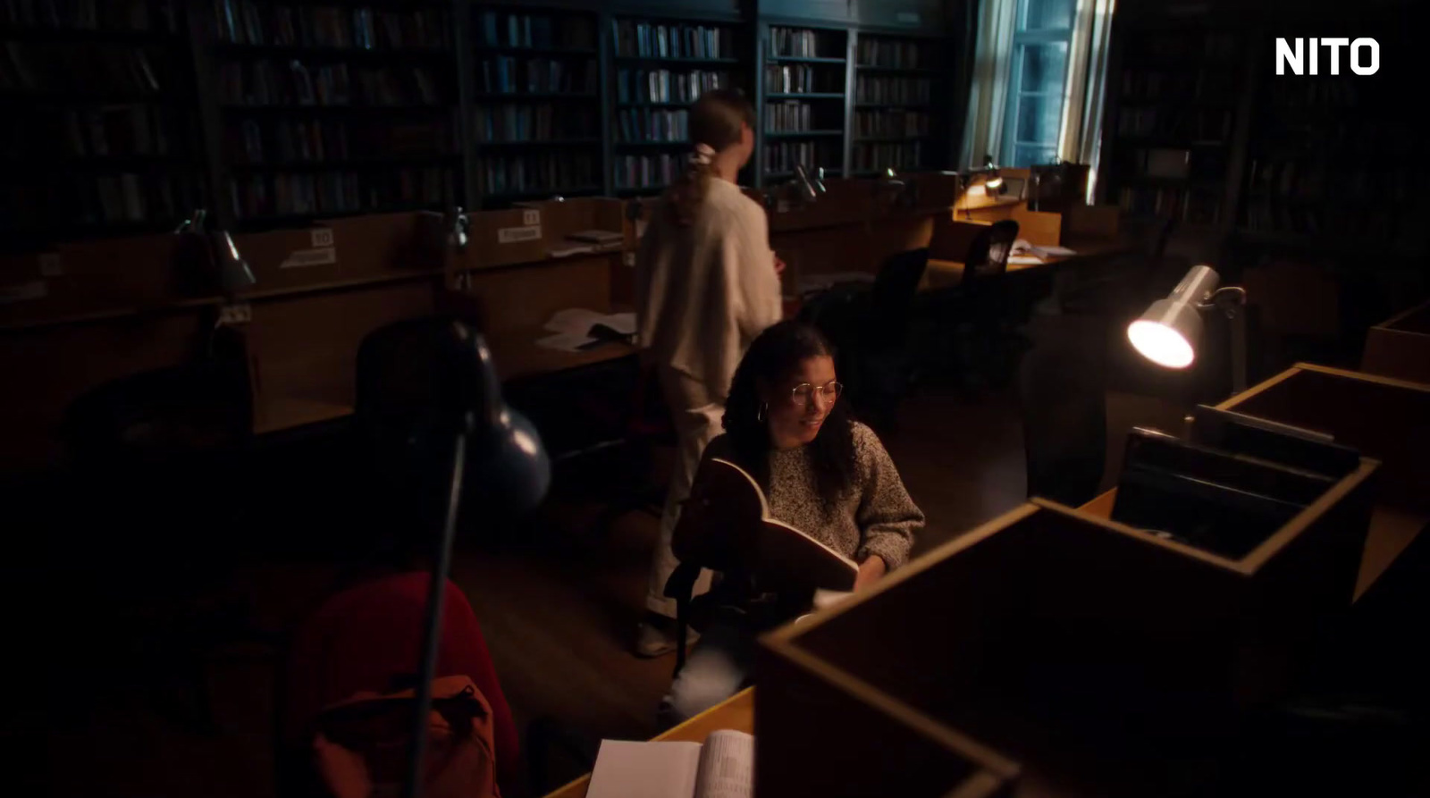 a woman sitting in a library reading a book