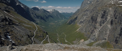 a person is walking down a mountain road in norway