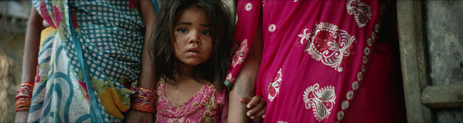 a little girl is peeking out from behind a curtain