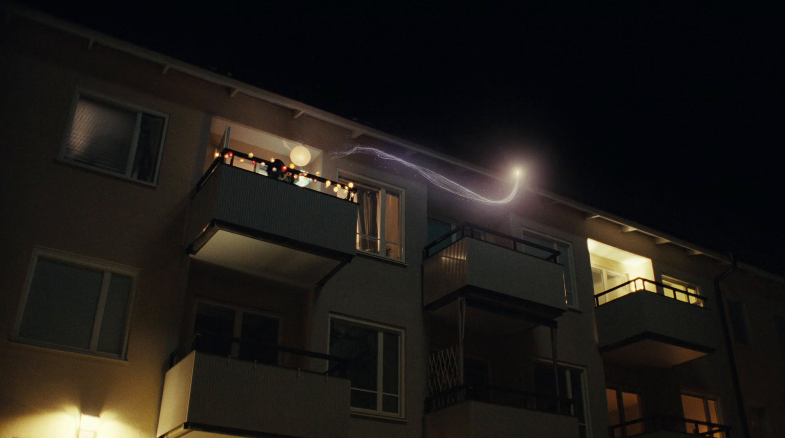 an apartment building at night with people on the balconies