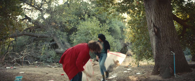 two people in a wooded area with a surfboard