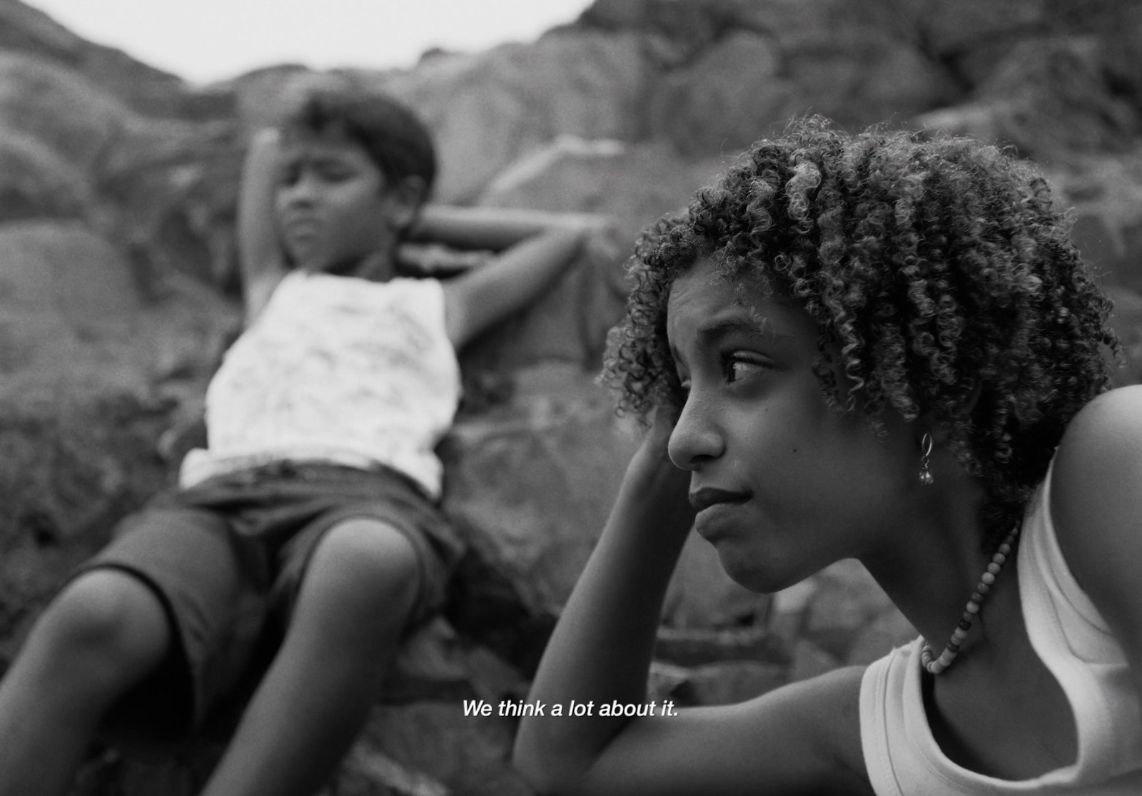 a black and white photo of two children sitting on rocks