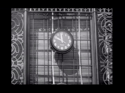 a black and white photo of a clock on a window